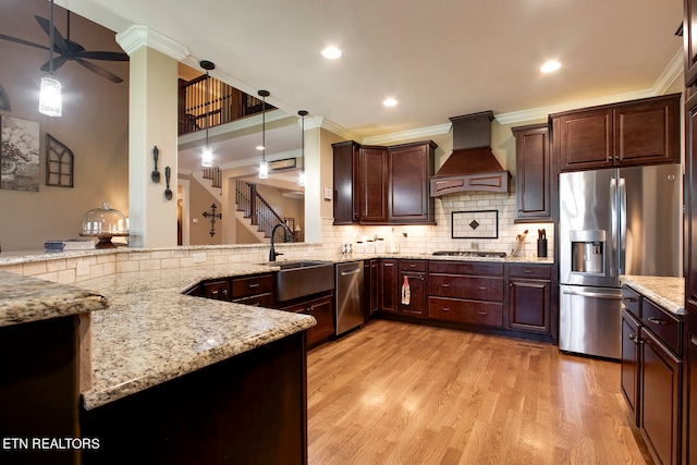 kitchen with light stone counters, stainless steel appliances, custom range hood, pendant lighting, and crown molding