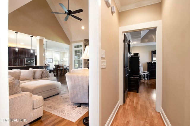 living room with light hardwood / wood-style floors, high vaulted ceiling, ornamental molding, and ceiling fan