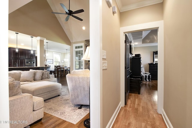 living area featuring light wood-style flooring, a ceiling fan, and crown molding