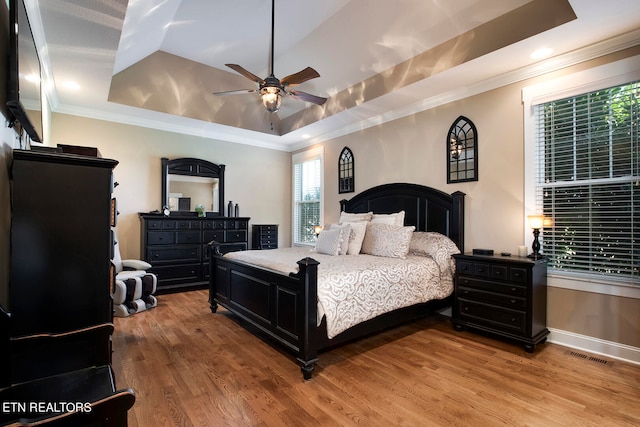 bedroom featuring ceiling fan, hardwood / wood-style flooring, a tray ceiling, and crown molding