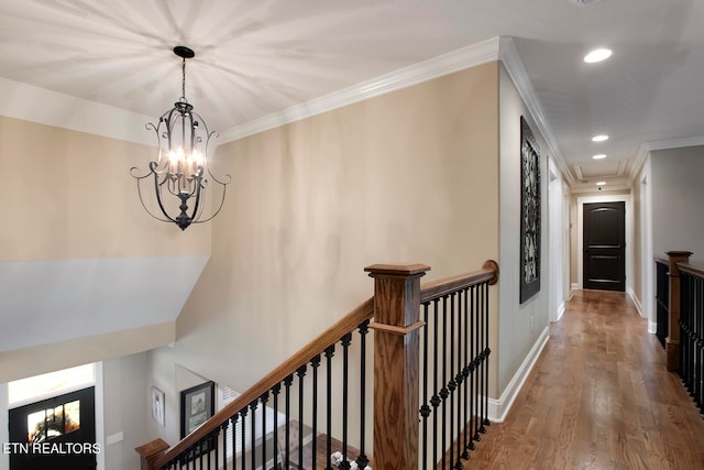 hall with an inviting chandelier, ornamental molding, and hardwood / wood-style flooring