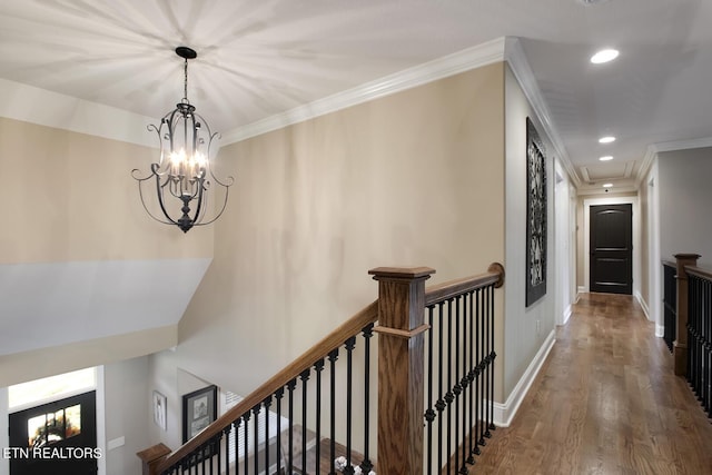 corridor featuring an inviting chandelier, ornamental molding, recessed lighting, an upstairs landing, and wood finished floors