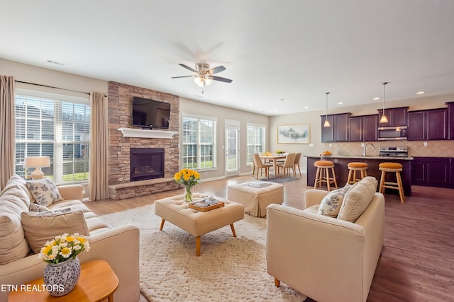 living room featuring a wealth of natural light, ceiling fan, a fireplace, and wood-type flooring