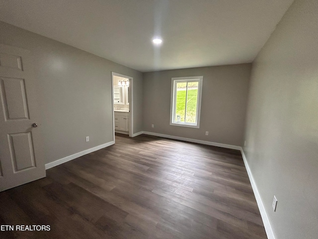 unfurnished bedroom with ensuite bath and dark wood-type flooring