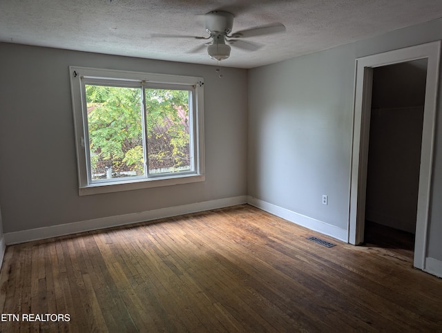 unfurnished room with visible vents, a textured ceiling, wood-type flooring, baseboards, and ceiling fan