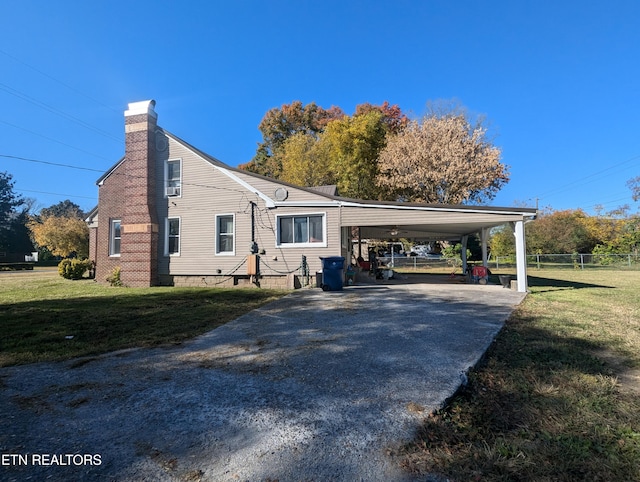 exterior space featuring fence, a lawn, a chimney, a carport, and driveway