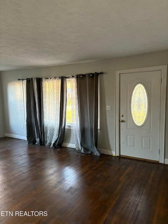 entrance foyer featuring dark wood-style floors, baseboards, and a textured ceiling