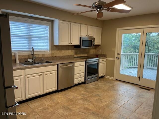 kitchen with a healthy amount of sunlight, appliances with stainless steel finishes, sink, and white cabinets