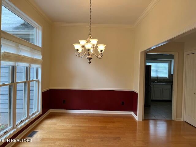 spare room featuring hardwood / wood-style floors, a notable chandelier, and plenty of natural light