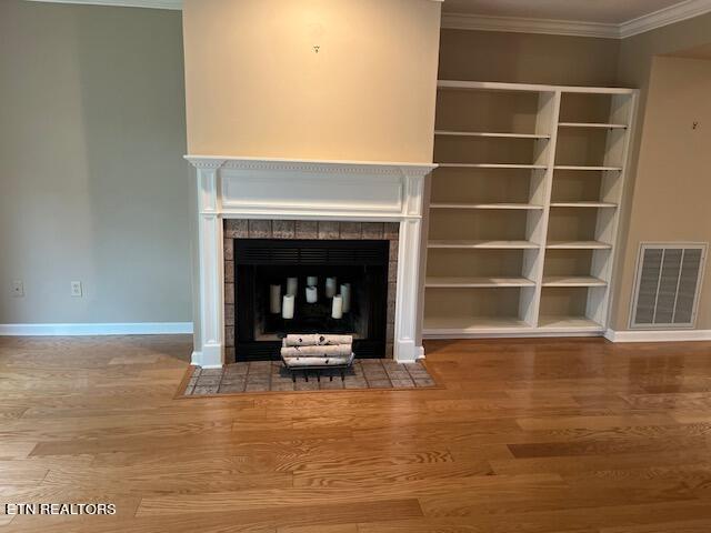 unfurnished living room with crown molding, hardwood / wood-style flooring, and a fireplace