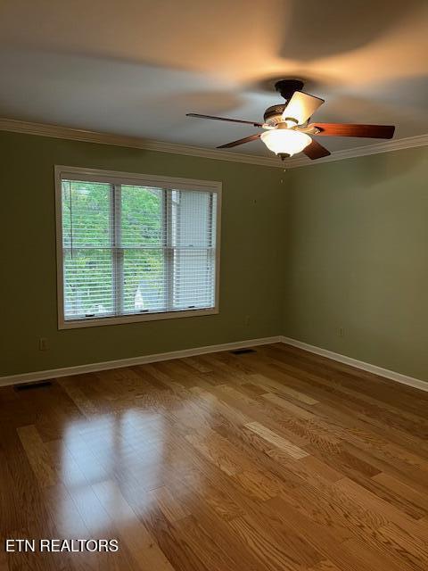 empty room featuring wood-type flooring, ornamental molding, and ceiling fan