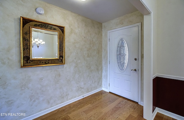 entrance foyer with a chandelier, baseboards, and wood finished floors