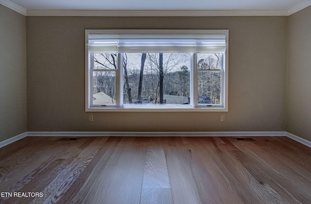 unfurnished room with plenty of natural light, dark wood-style floors, baseboards, and ornamental molding