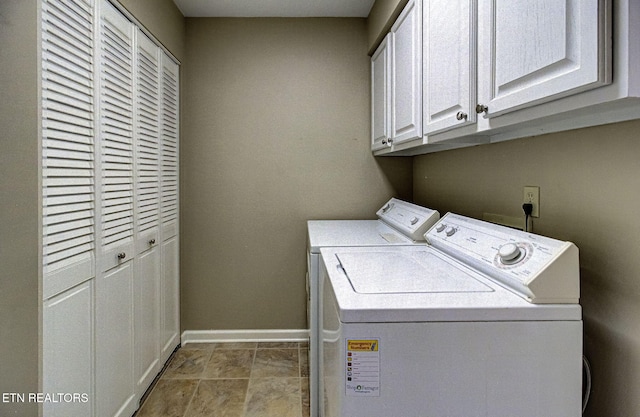 clothes washing area with washer and clothes dryer, cabinet space, and baseboards