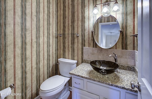 half bathroom featuring decorative backsplash, toilet, and vanity