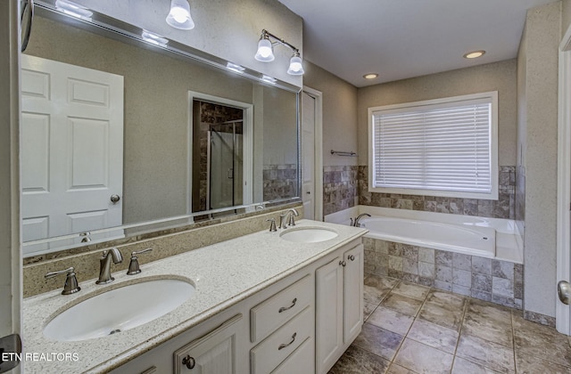 bathroom featuring a sink, a garden tub, a stall shower, and double vanity