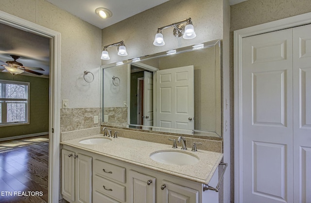 full bathroom featuring ceiling fan, double vanity, wood finished floors, and a sink