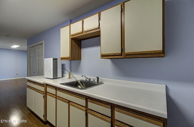 kitchen with light countertops, dark wood-style floors, baseboards, and a sink