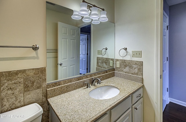 half bathroom with tile walls, visible vents, toilet, and vanity