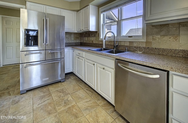 kitchen with a sink, tasteful backsplash, white cabinetry, and stainless steel appliances