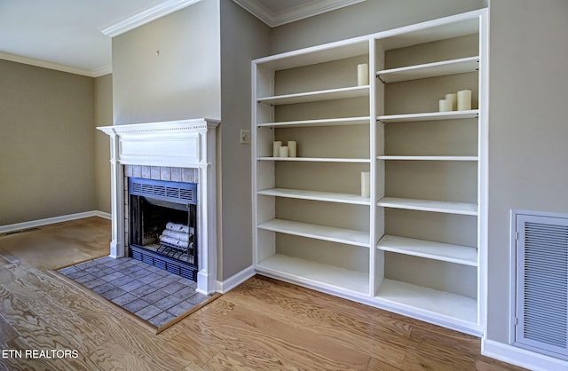 interior details with a tiled fireplace, visible vents, baseboards, and ornamental molding