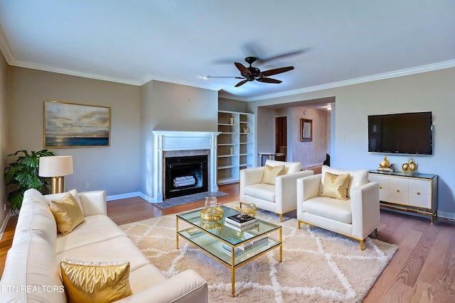 living area with a tiled fireplace, wood finished floors, and ornamental molding