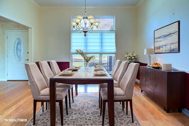 dining space with a notable chandelier, ornamental molding, and light wood finished floors