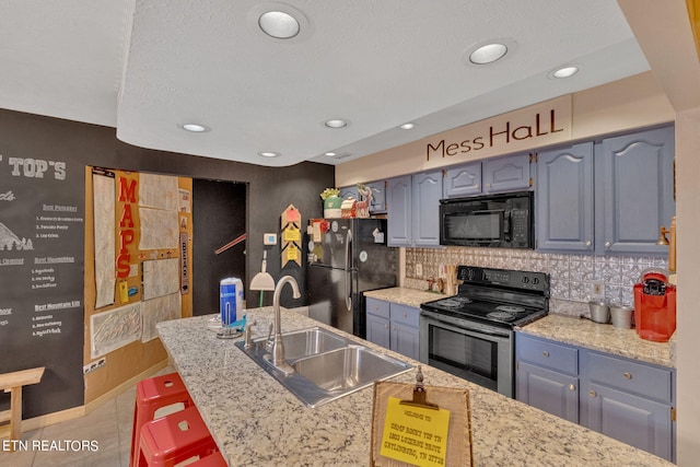 kitchen featuring black appliances, tasteful backsplash, sink, and light stone countertops