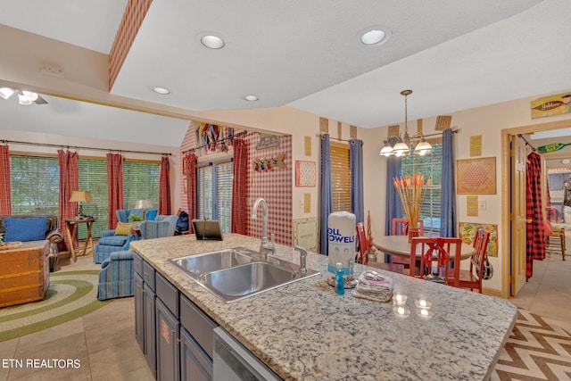 kitchen with pendant lighting, light tile patterned flooring, a kitchen island with sink, and sink