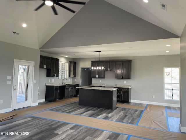 kitchen with pendant lighting, hardwood / wood-style flooring, sink, a kitchen island, and high vaulted ceiling