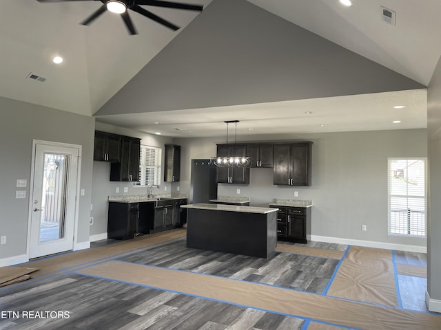 kitchen with a center island, visible vents, baseboards, ceiling fan, and high vaulted ceiling