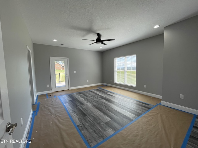 unfurnished room with ceiling fan, baseboards, and a textured ceiling