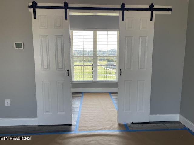doorway with wood finished floors, baseboards, and a barn door