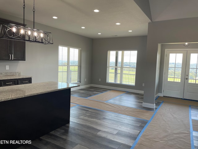 kitchen with pendant lighting, hardwood / wood-style flooring, light stone countertops, and a wealth of natural light