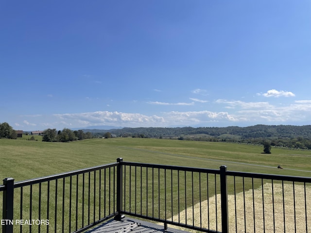 wooden terrace with a rural view and a lawn