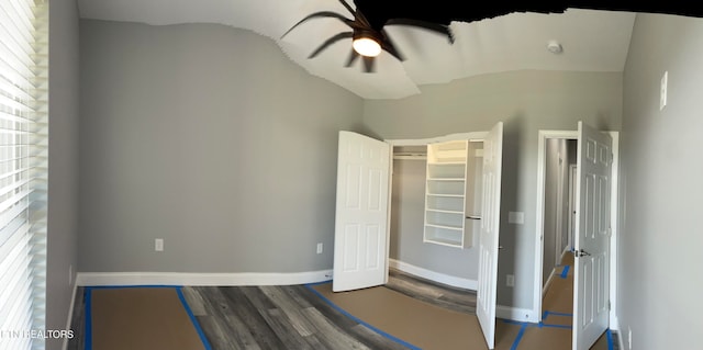 unfurnished bedroom with multiple windows, lofted ceiling, ceiling fan, and dark wood-type flooring