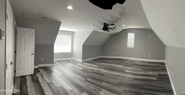 additional living space featuring vaulted ceiling, baseboards, a wealth of natural light, and dark wood-style flooring