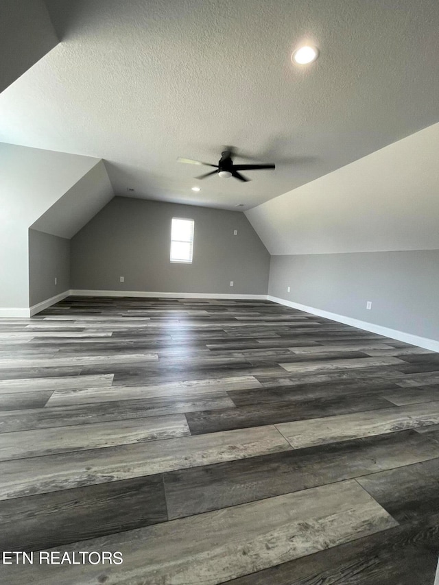 bonus room with ceiling fan, a textured ceiling, lofted ceiling, and dark hardwood / wood-style floors