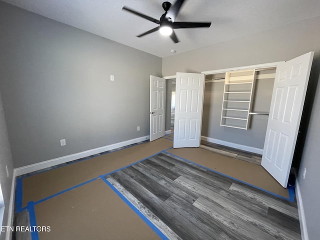 unfurnished bedroom featuring baseboards, a ceiling fan, wood finished floors, and a closet