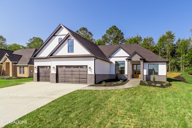 modern farmhouse featuring brick siding, roof with shingles, a front yard, a garage, and driveway