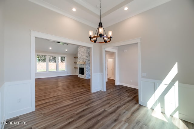 unfurnished living room with a stone fireplace, recessed lighting, a wainscoted wall, a decorative wall, and wood finished floors