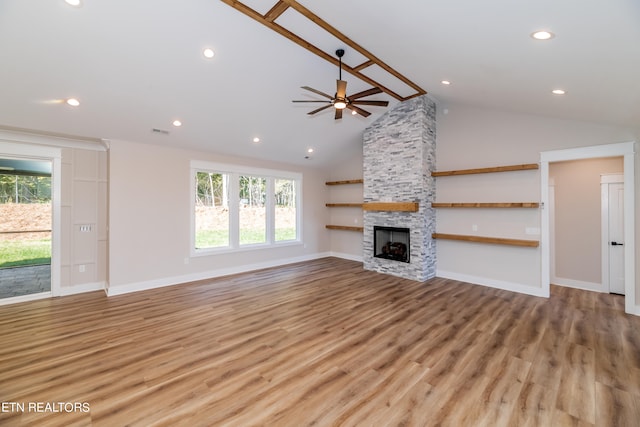 unfurnished living room featuring ceiling fan, a stone fireplace, light wood-type flooring, and high vaulted ceiling