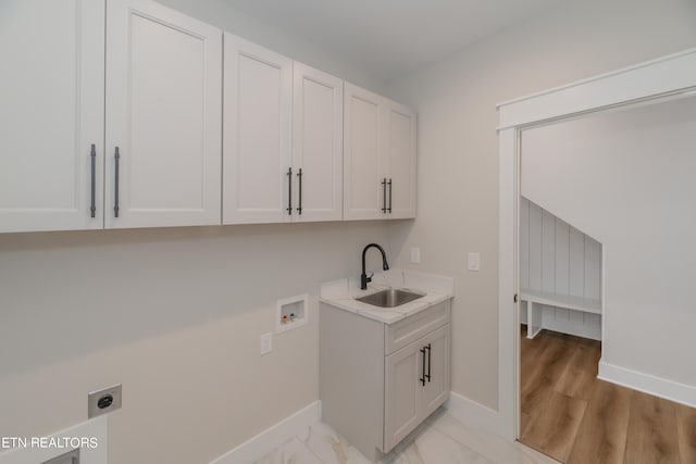 washroom featuring hookup for an electric dryer, sink, light hardwood / wood-style floors, washer hookup, and cabinets