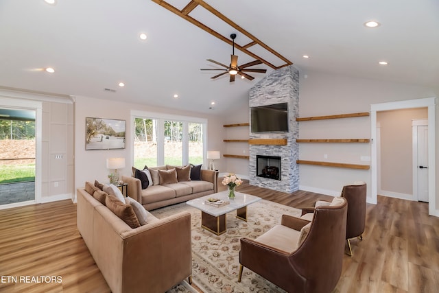 living area with visible vents, ceiling fan, a stone fireplace, and wood finished floors