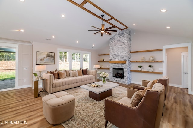 living area with ceiling fan, a stone fireplace, light wood finished floors, and visible vents