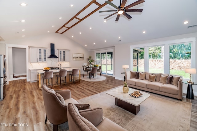 living room with recessed lighting, visible vents, light wood-style flooring, high vaulted ceiling, and baseboards