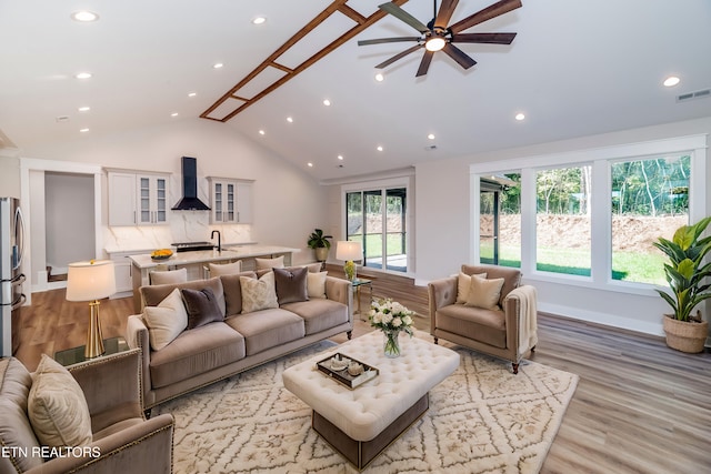 living room featuring baseboards, visible vents, vaulted ceiling, light wood-style floors, and recessed lighting