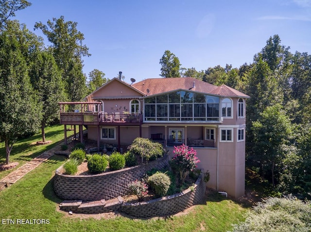 back of property featuring a lawn, a sunroom, and a wooden deck