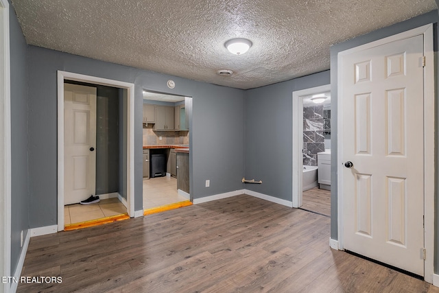 unfurnished bedroom with light hardwood / wood-style flooring, connected bathroom, a closet, and a textured ceiling