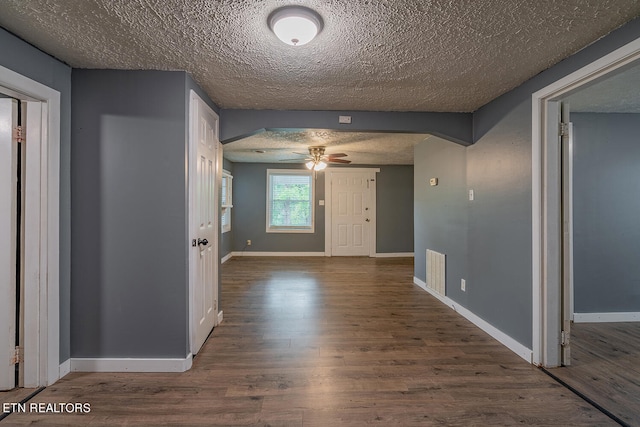 hall featuring a textured ceiling and dark wood-type flooring